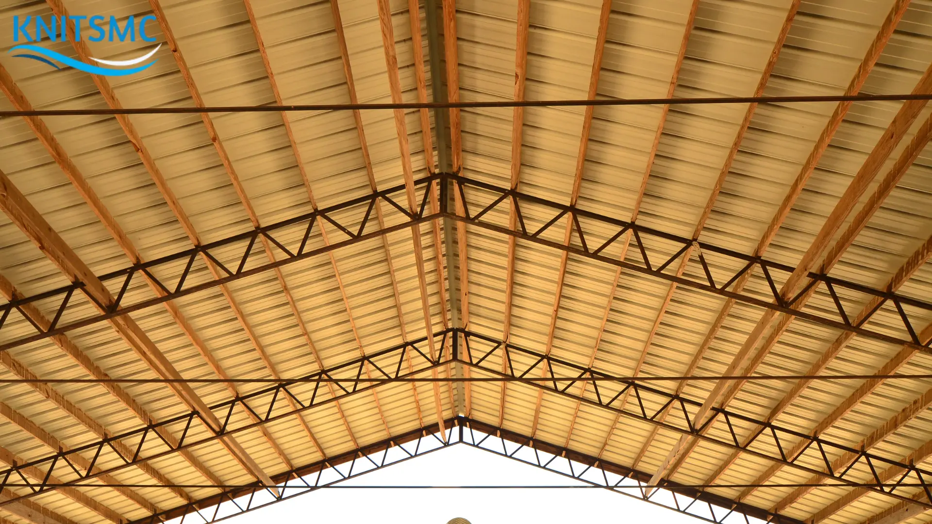 Barn Style Roof: Interior view of a barn-style roof with exposed wooden beams and metal trusses, showcasing the traditional architectural design often used for agricultural and storage buildings.