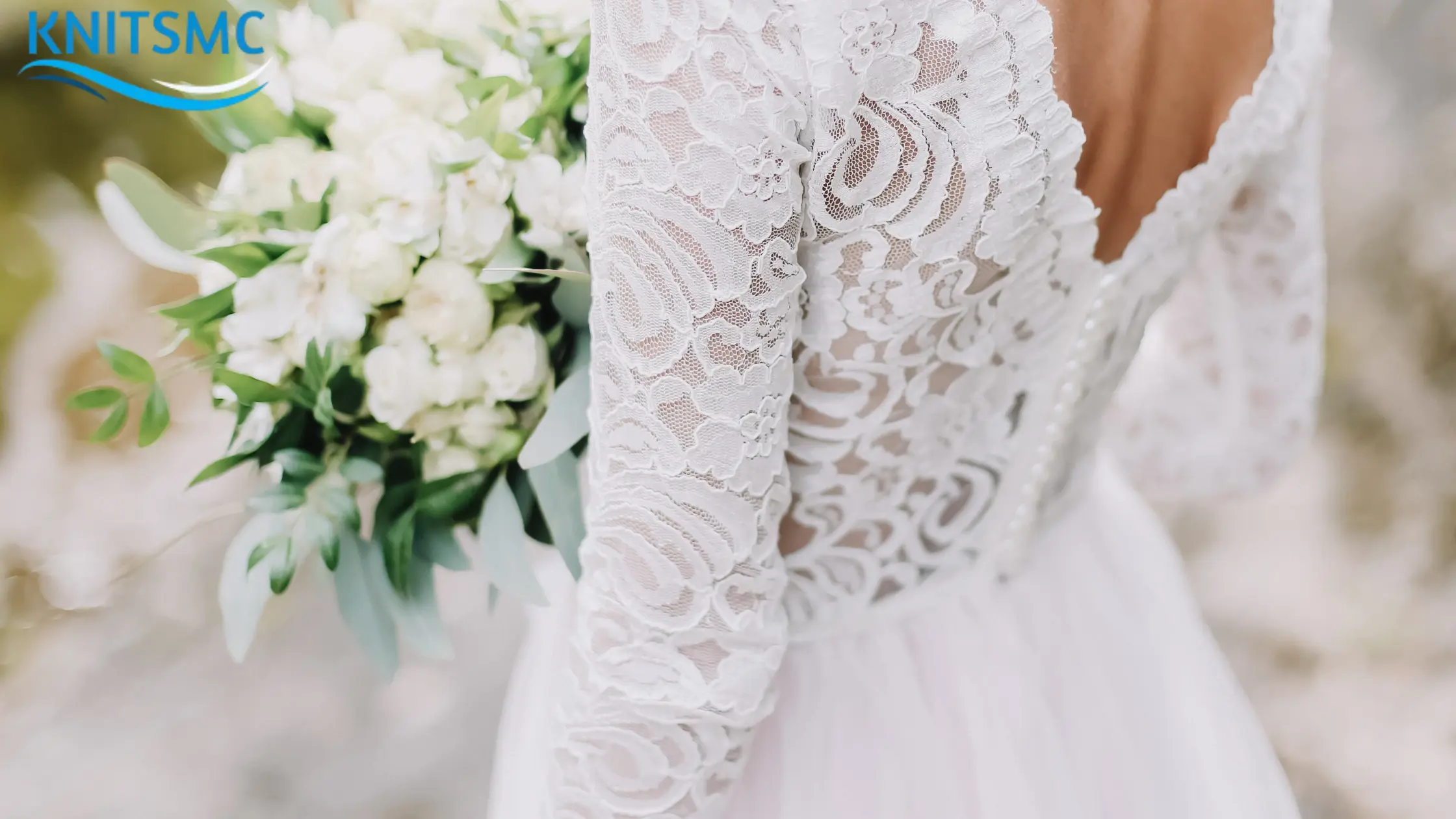 A bride in a white lace wedding dress holds a bouquet of white flowers with greenery, raising the question: Can You Wear White to a Wedding?